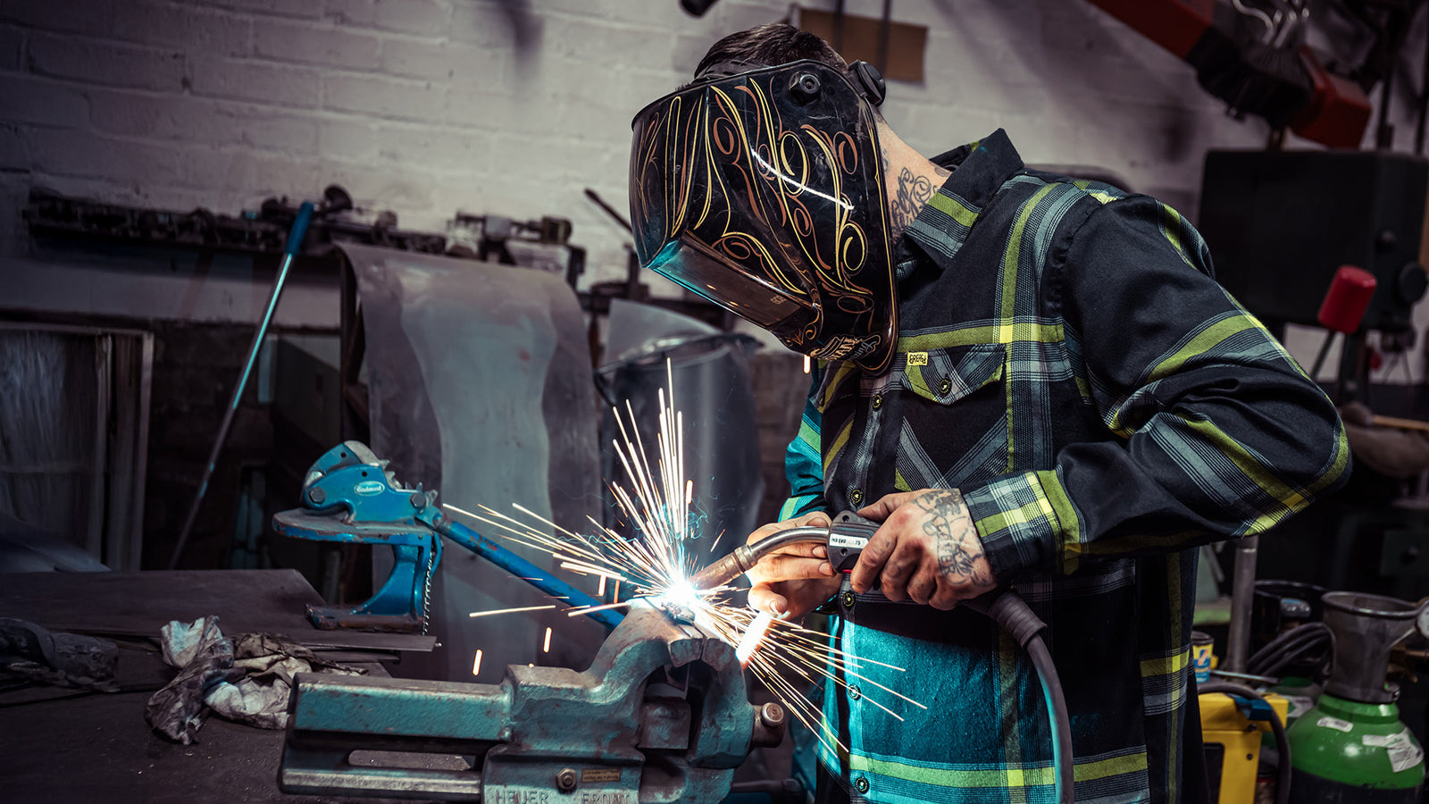 eat dust black, yellow and white flannel on a person who is welding