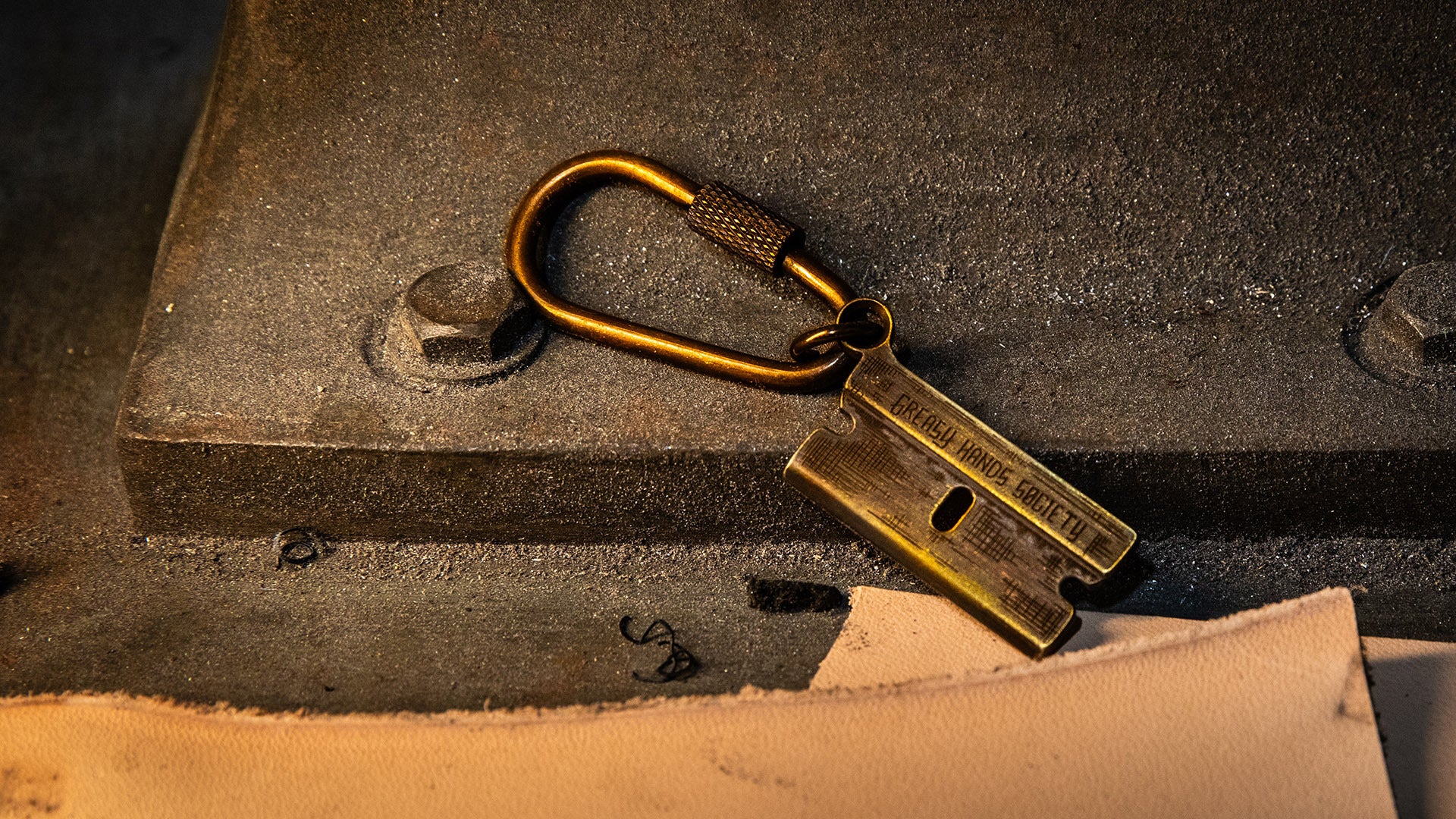 bronze razor blade keychain or necklace lying on a workbench with leather